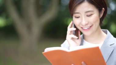 Telefonla konuşurken defterini açan bir kadın çalışan.