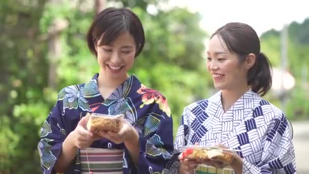 ヨーヨーで歩く浴衣の女性と揚げ麺 — ストック動画