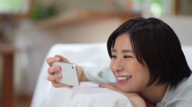 Akıllı telefonuyla video izleyen bir kadın.