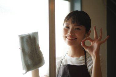 Bir kadın cam kapıyı temizliyor. 