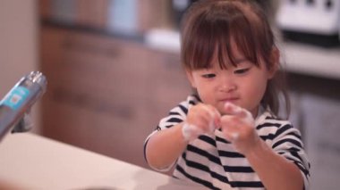 Ellerini yıkayan bir kız resmi. 