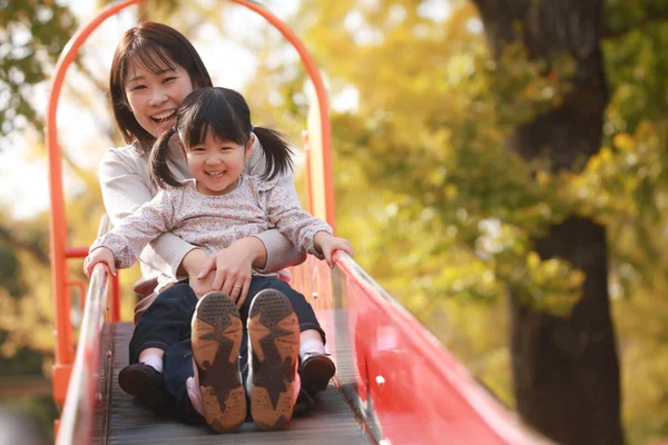 Aileler ve çocuklar kaydırağın üzerinde oynuyorlar