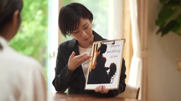 Jovem Empregado Japonês Terno Preto Mostrando Plano Casamento Para Clientes — Vídeo de Stock
