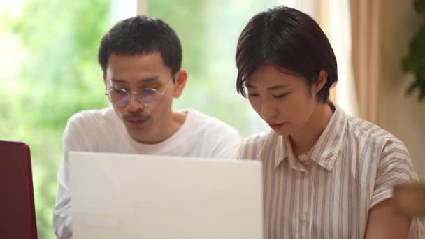 家庭でノートパソコンを使う幸せな日本人夫婦 — ストック動画