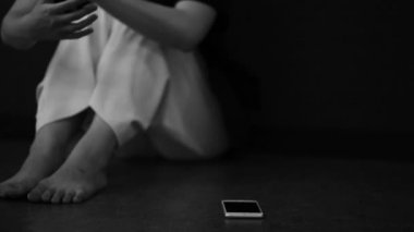 A woman who puts her smartphone on the floor and is depressed 