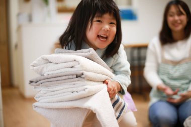 Girl carrying folded laundry 