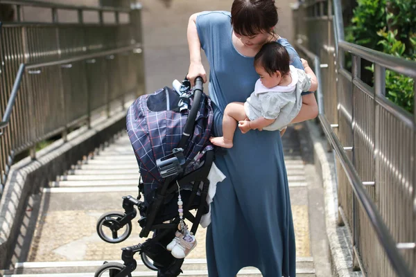 Mother lifting a stroller and climbing stairs