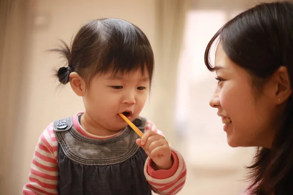 Image of a girl and her mother brushing their teeth 