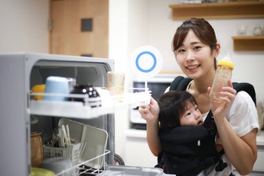 Çocuklu Asyalı kadın bulaşık makinesini çalıştırmaya hazır ol.