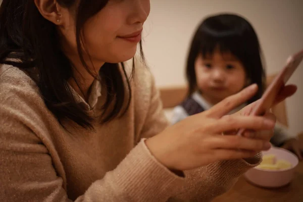 Ung Asiatisk Mamma Använder Smartphone Hemma Med Sin Dotter Bakgrunden — Stockfoto