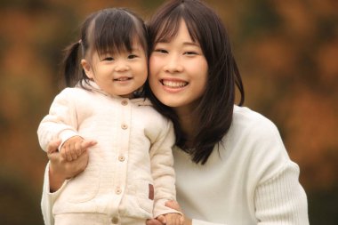 Portrait of happy young mother with her little daughter in the park
