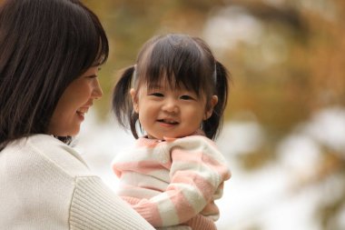 Portrait of happy young mother with her little daughter in the park