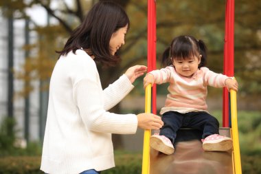 Happy young mother playing with her little daughter in the park