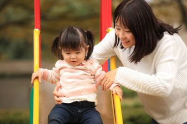 Happy young mother playing with her little daughter in the park