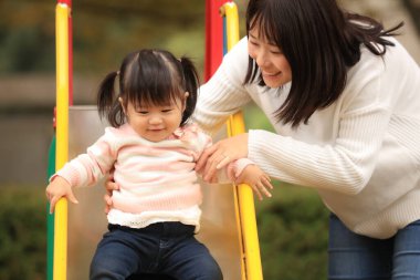 Happy young mother playing with her little daughter in the park