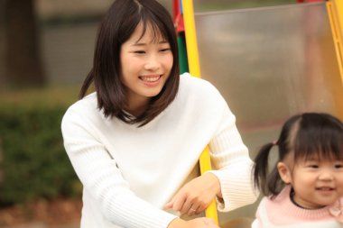 Happy young mother playing with her little daughter in the park