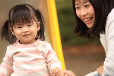 Happy young mother playing with her little daughter in the park