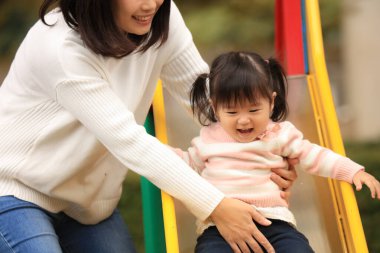 Happy young mother playing with her little daughter in the park