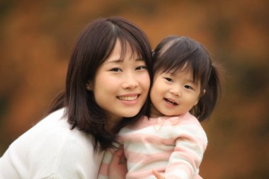 Portrait of happy young mother with her little daughter in the park