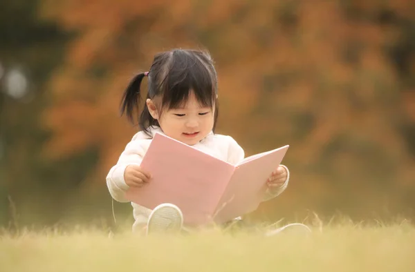 Little Japanese Girl Reading Pink Book Park — стоковое фото