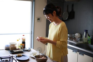 Genç Asyalı kadın mutfakta yemek pişiriyor. 