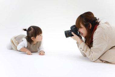 Stüdyoda küçük bir kızla çalışan kadın fotoğrafçı.