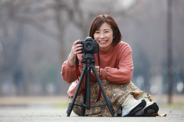 Ormanın arka planında kamerası olan genç bir kadın. 