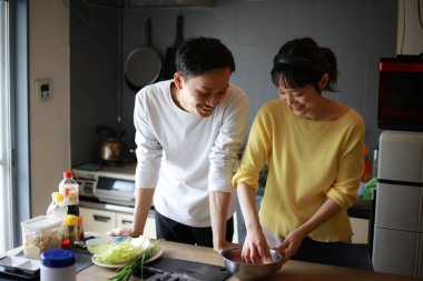 Genç bir çift evdeki mutfakta yemek pişiriyor.