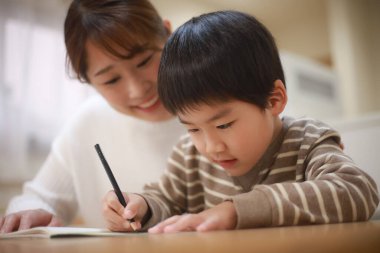 Annesiyle birlikte çizen yakışıklı Asyalı çocuk.