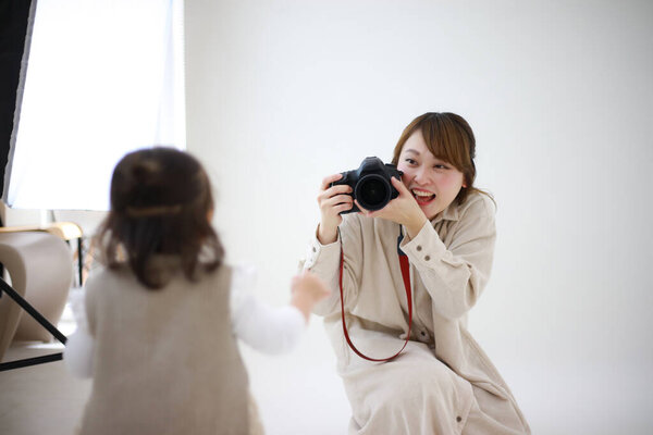 Woman photographer working in the studio with little girl
