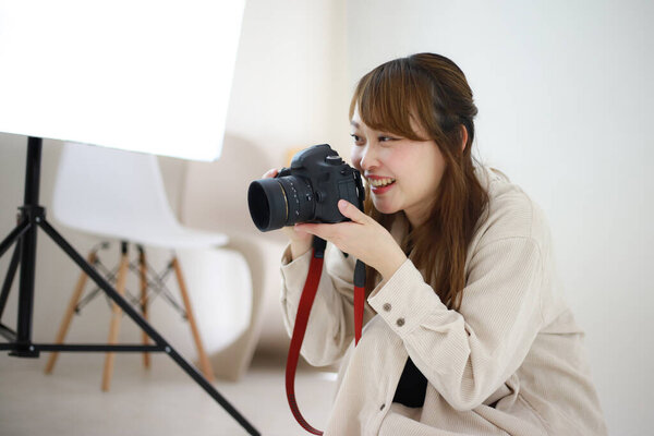 beautiful young woman photographer with camera in studio 