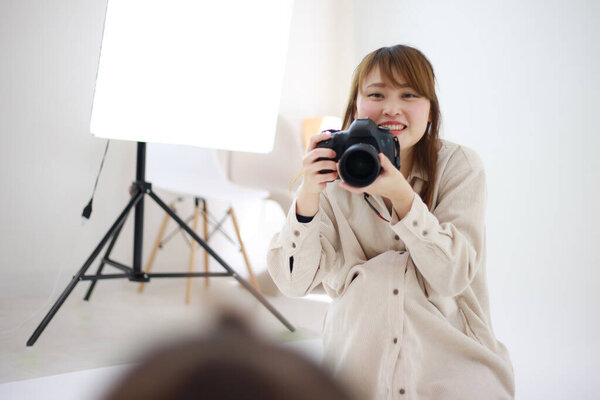 beautiful young woman photographer with camera in studio 