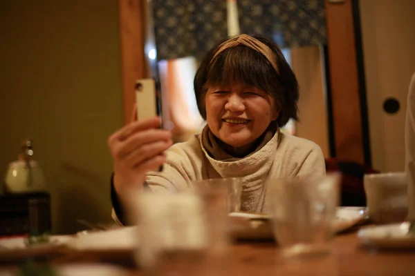 Старшая Азиатка Сидит Столом Использует Смартфон — стоковое фото
