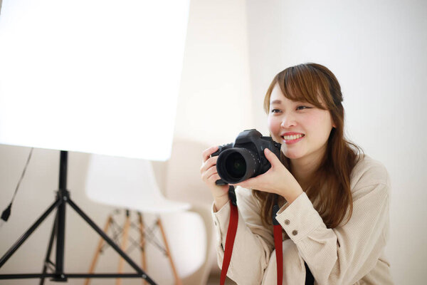 beautiful young woman photographer with camera in studio 