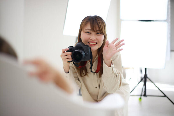 beautiful young woman photographer with camera in studio 