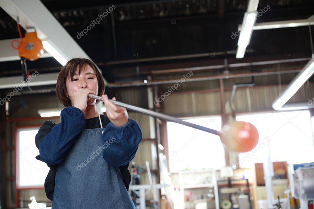 A woman making a glass container blown glass