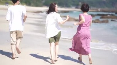 Erkekler ve kadınlar sahilde koşuyor.