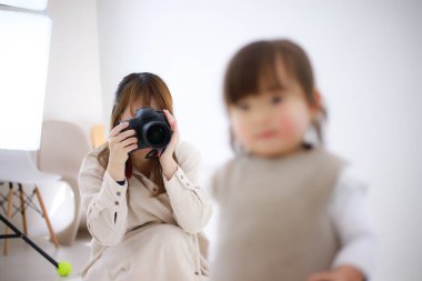 Stüdyoda küçük bir kızla çalışan kadın fotoğrafçı.