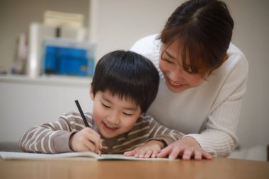 Annesiyle birlikte çizen yakışıklı Asyalı çocuk.