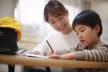 Annesiyle birlikte çizen yakışıklı Asyalı çocuk.