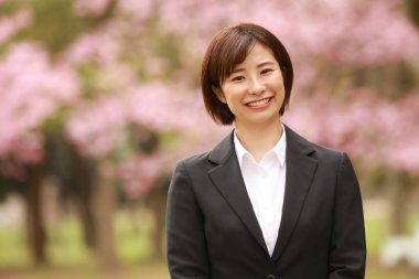 Güzel Asyalı iş kadını parkta duruyor. 