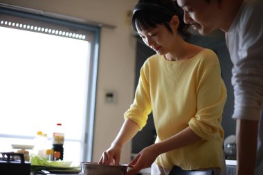 Genç bir çift evdeki mutfakta yemek pişiriyor.