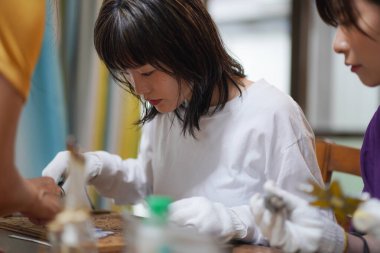 Genç Asyalı kadın lehimleme demiri kullanarak güzel bir dekorasyon yapıyor.