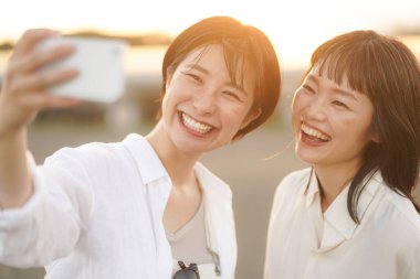 İki genç Asyalı kadın gün batımında poz veriyor.