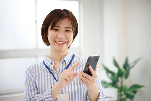 亚洲的年轻女性 办公室里有智能手机 — 图库照片