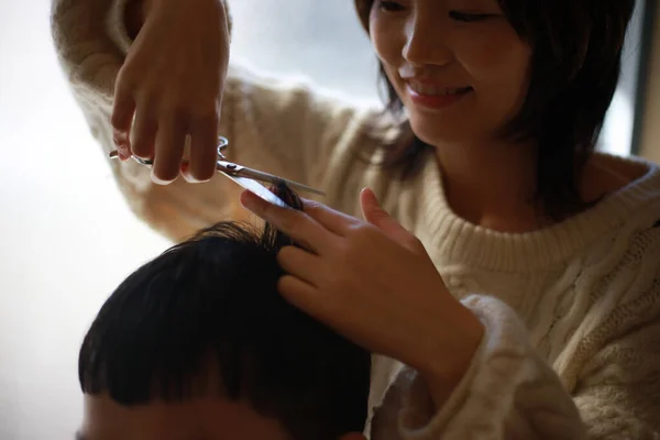Молодая Азиатка Держит Ножницы Стрижет Волосы Улыбающемуся Мужчине — стоковое фото
