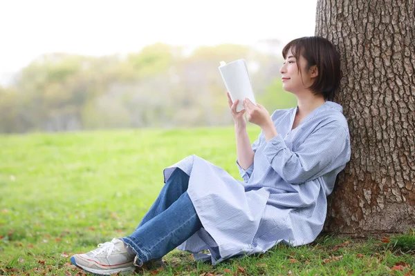 Uśmiechnięta Kobieta Czytająca Książkę Parku — Zdjęcie stockowe