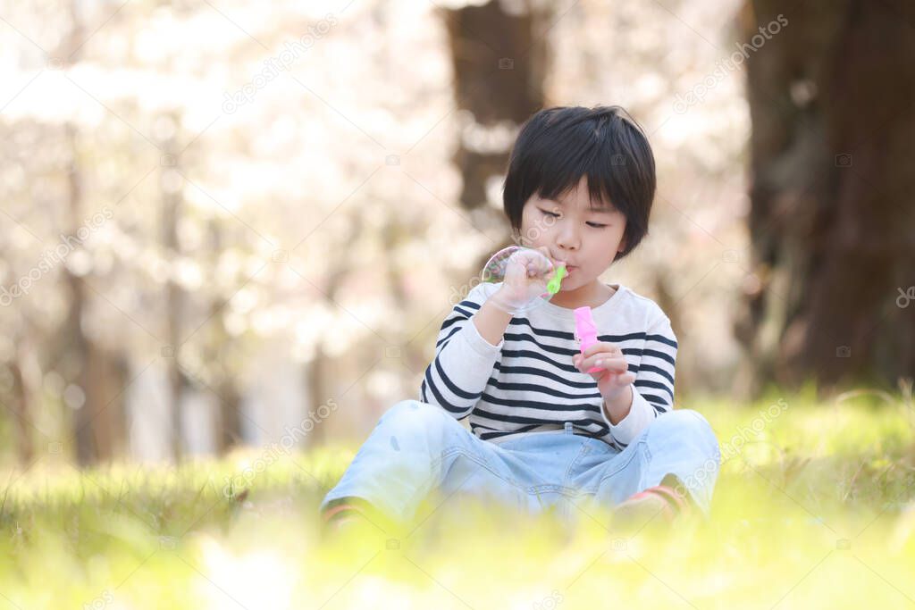 cute boy blowing bubble in park.