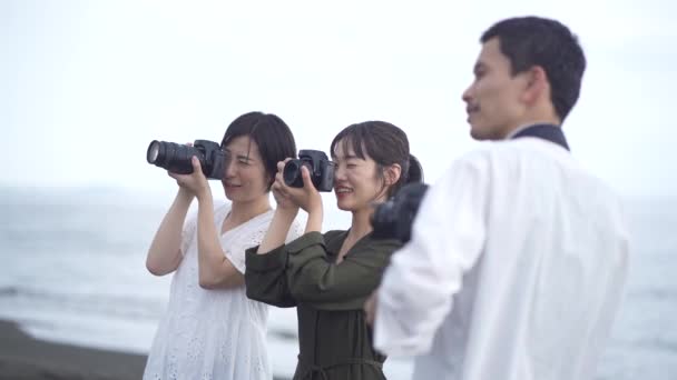 Улыбающиеся Молодые Азиатские Фотографы Стоящие Берегу Моря Фотографирующие Цифровыми Камерами — стоковое видео