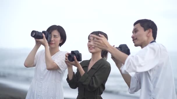 Gülümseyen Asyalı Genç Fotoğrafçılar Deniz Kıyısında Durup Dijital Kameralarla Fotoğraf — Stok video